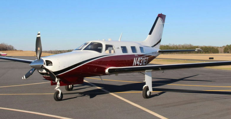 A single-engine piston aircraft sitting on an airport tarmac.